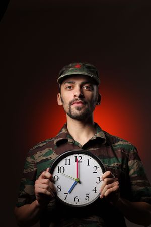 Portrait of a soldier holding clock set at 7AMの写真素材