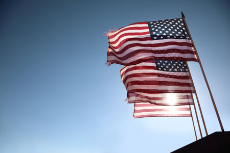 Four American flags waving over blue sky