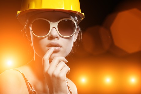 Portrait of fashionable female construction worker over glowing lights backgroundの写真素材