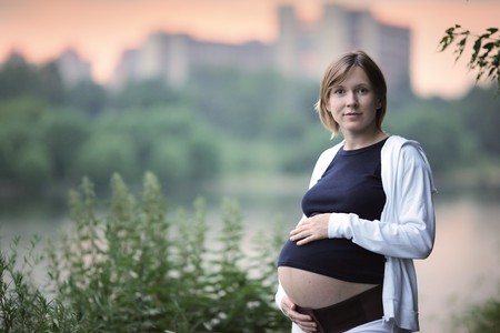 Pregnant woman in park near river at twilight. Shallow DOF.の写真素材