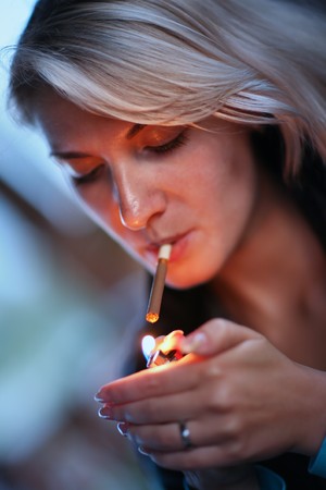 Beautiful woman lighting cigarette. Close-up, shallow DOF.の写真素材