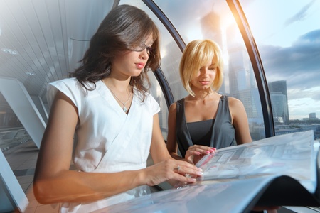 Two businesswomen looking into papers in futuristic interiorの写真素材