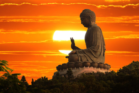 Buddha statue over scenic sunset sky backgroundの写真素材