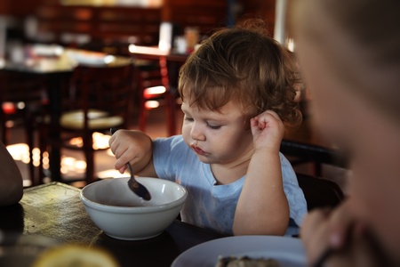 Cute 15 months old baby girl eating in restaurant.の写真素材