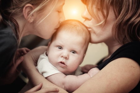 Portrait of mother and daughter kissing baby girl sister  Closeup の写真素材
