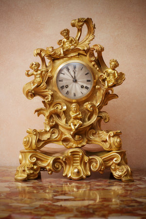 Vintage ornate golden clock on marble table, closeup.