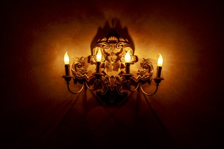 Vintage style lamp with candlesticks illuminating dark wall backgroundの写真素材