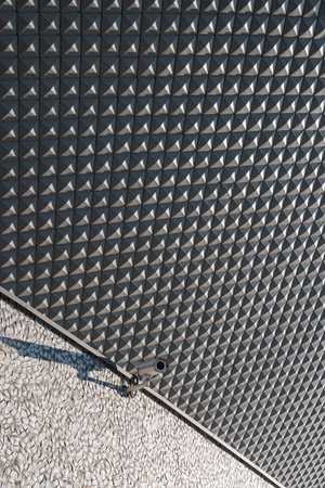 Street camera attached to a building, geometric elevation tiles in background