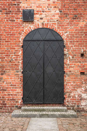 Iron door in a red brick wall. Gothic castle of Pomeranian dukes in DarÅowo, Poland.の写真素材