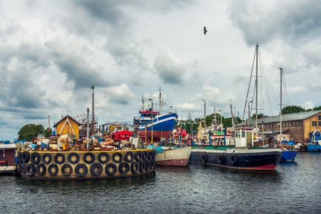 View of the shipyards in the port of DarÅ‚owo, colorful ships and concrete quay. Lonely bird in...