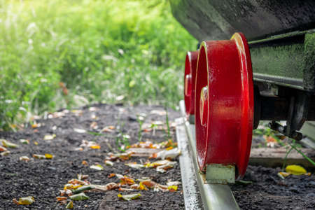 the undercarriage of a traditional mine cart. a restored, old mine car on a fragment of a railway track. the red steel wheels and the black plate of the wagon's chest.の写真素材