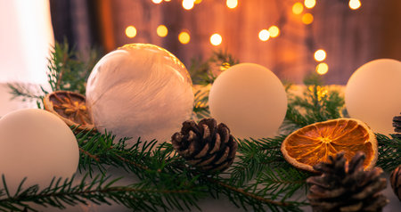 Christmas decoration set made of white Christmas balls, spruce sprigs, cones and dried oranges and lemons. Lightened lights in the background.の写真素材