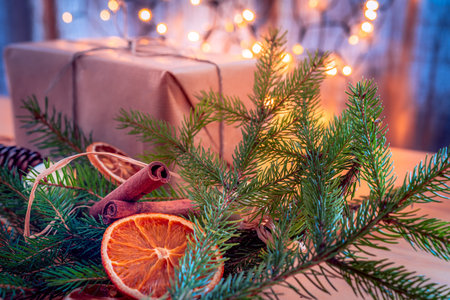 Christmas composition - present, spruce sprigs, dried fruit and cinnamon rolls. Christmas lights in the bachground.の写真素材