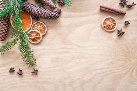 Christmas decoration set made of spruce sprig, cones, dried oranges and lemons, cinnamon rolls and anise stars. Plywood in the background.の写真素材