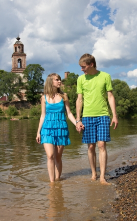 Beautiful girl walking with a young, confident guy on the river in the countrysideの写真素材