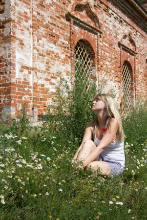 The beautiful girl sitting on the bank of the river on a sunny dayの写真素材