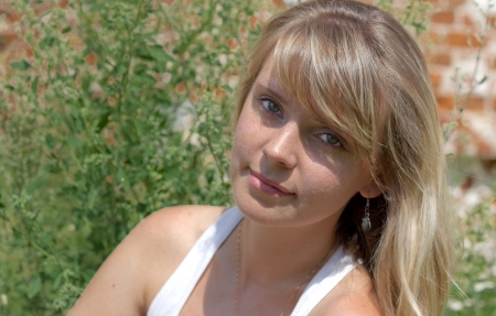 The beautiful girl sitting on the bank of the river on a sunny dayの写真素材