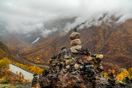 Stunning Autumn Landscape Featuring Stone Stacks Amidst Foggy Mountains and Lush Natureの写真素材