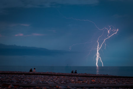 A striking and powerful lightning bolt lights up the sky over the oceanの写真素材