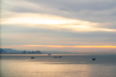A sunset with vibrant colors over water filled with gently floating boatsの写真素材