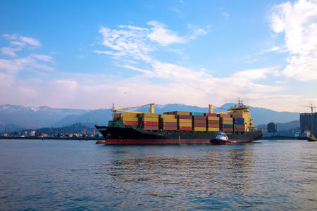 A vibrant container ship is docked at the port, surrounded by a stunning and scenic backgroundの写真素材