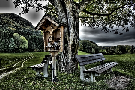 Cross roadside with tree and benchの写真素材