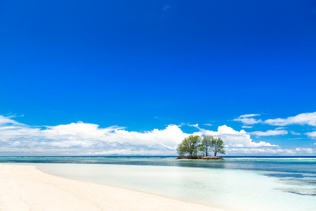 The Seychelles. White coral sand beach and turquoise sea. A small island on the horizon.の写真素材