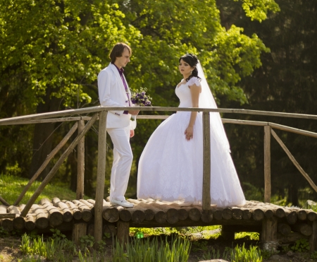 Happy bride and groom on a wooden bridge in the park at the wedding walkの写真素材