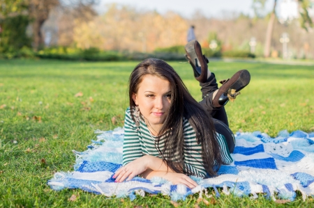 young woman laying down on the ground in autumn parkの写真素材