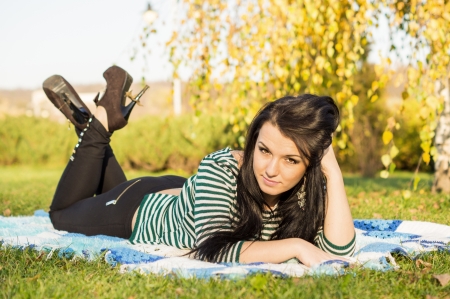 young woman laying down on the ground in autumn parkの写真素材