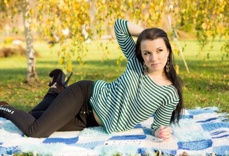 young woman laying down on the ground in autumn parkの写真素材