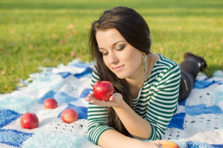 Autumn woman happy smiling outdoors, beautiful Woman holding autumn apples and fruits. Portrait of young woman walking outdoors at fall. Attractive woman walking in autumn park.の写真素材