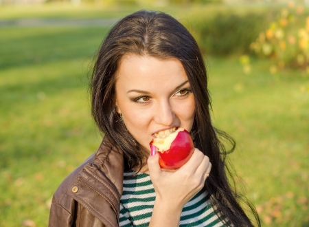 Autumn woman happy smiling outdoors, beautiful Woman holding autumn apples and fruits. Portrait of young woman walking outdoors at fall. Attractive woman walking in autumn park.の写真素材