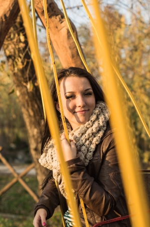 Smiling young model relaxing in a sunny garden sitting on swingの写真素材