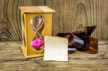 Hourglass and 35mm film with space for text on the wooden backgroundの写真素材