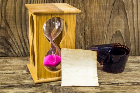 Hourglass and 35mm film with space for text on the wooden backgroundの写真素材