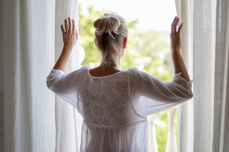 Newly lifted woman looking out the window in pijama.の写真素材