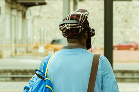 YOUNG MAN WITH HEADPHONES LISTENING TO MUSIC IN THE TRAIN STATIONの写真素材