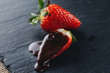 juicy fresh strawberries drenched with chocolate sauce on a gray stone backgroundの写真素材