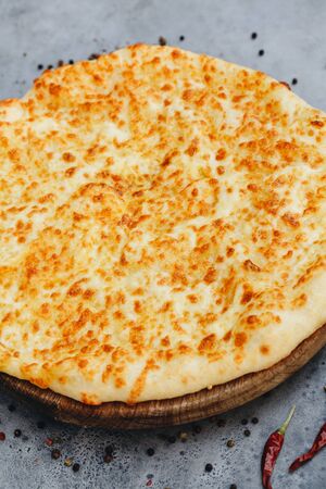 Sliced pie with cheese on a wooden board on grey background. Khachapuriの写真素材
