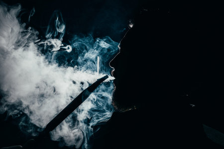 silhouette of a man exhaling smoke on a dark background closeup.