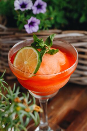 frozen strawberry Margarita cocktail close-up next to flowers on wooden background.の写真素材