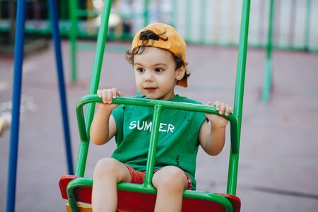 beautiful little boy spinning on a summer swing with space for textの写真素材