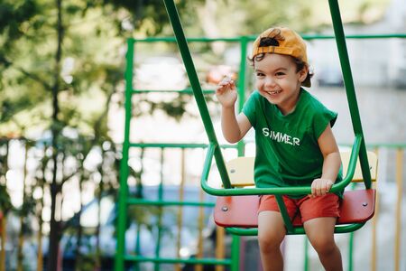 beautiful little boy spinning on a summer swing with space for textの写真素材