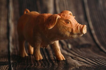 figurine of a toy pig on a wooden background.の写真素材