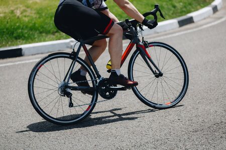 Detail of a road bike with a cyclist pedaling on a roadの写真素材