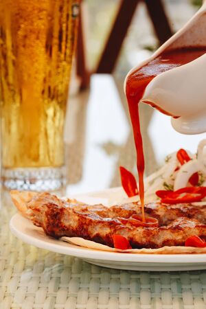 kebab meat with ketchup on a white plate pour sauce in the restaurant.の写真素材