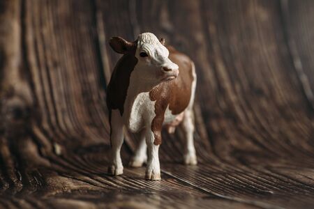 figure of a toy cow on a wooden background.の写真素材