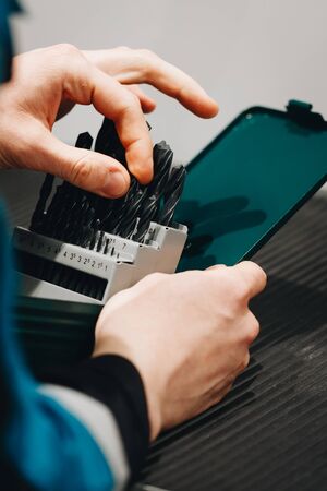 the hand of the worker selects the drill bit from the set.の写真素材