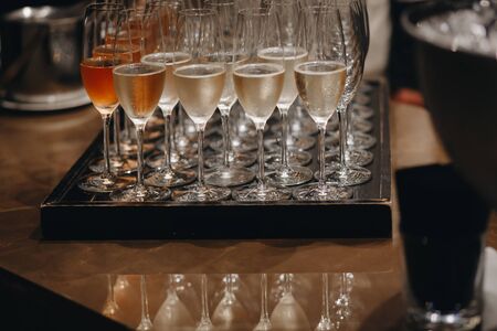 Pouring champagne into wine glasses. Champagne flutes on a wedding or new year eve party.の写真素材